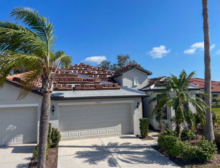 Roofers actively replacing a clay tile roof, demonstrating expertise and care in handling roofing materials during the renovation.